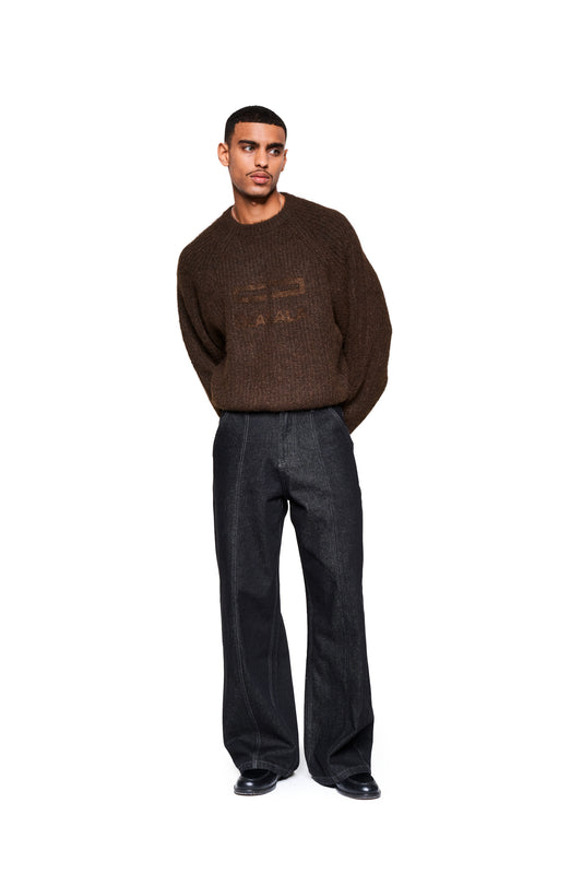 Junger Mann im Fuzzy Knit Sweater Brown mit cropped, boxy Schnitt und großer Logo-Stickerei, kombiniert mit weit geschnittenen Jeans, präsentiert von OLAKALA.