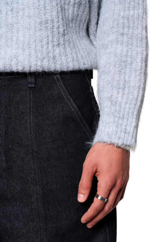 Person trägt den Fuzzy Knit Sweater Gray von OLAKALA, erkennbar an der cropped, boxy Silhouette und der großen Logo-Stickerei, kombiniert mit dunkler Jeans.