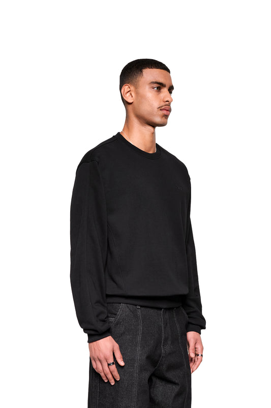 Männermodell im Mokka Sweater mit sichtbaren Nähten, silbernen Ringen und Kette. Minimalistischer Look des OLAKALA Offizieller Onlineshop.