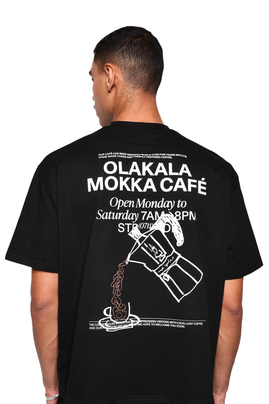 Mokka T-Shirt Black mit großem OLAKALA MOKKA CAFÉ-Aufdruck und Moka-Pot-Illustration auf der Rückseite; oversized, boxy Fit aus weichem Stoff.