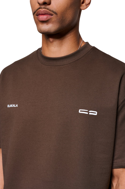 Mokka T-Shirt Brown mit OLAKALA Schriftzug und Logo auf der Brust, getragen von einem Mann mit Kette und leichtem Schnurrbart.