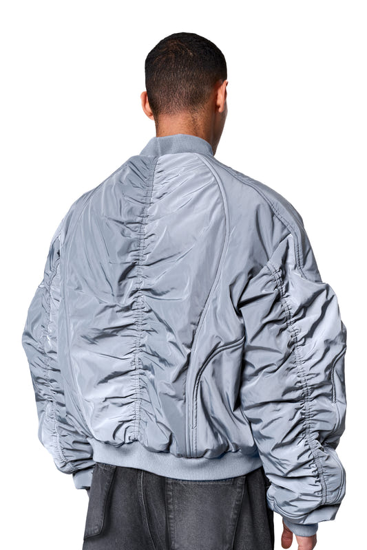Rear view of the Void Bomber Jacket Gray with a ribbed collar, elastic cuffs, and distinctive seam details, worn over dark pants.