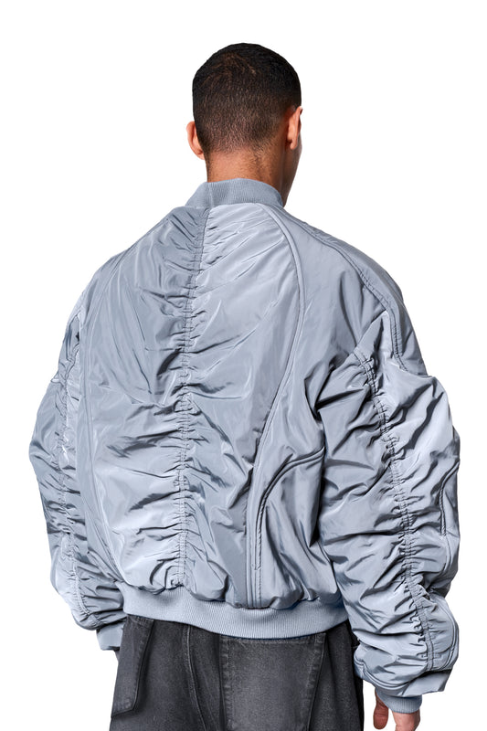 Rückansicht der Void Bomber Jacket Gray mit geripptem Kragen, elastischen Bündchen und markanten Teilungsnähten, getragen über dunkler Hose.