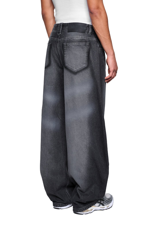 Person trägt Void Denim Pants mit weitem Bein, großen Taschen und Used-Optik, kombiniert mit weißen Sneakern. Jeans leicht verjüngt am Saum.