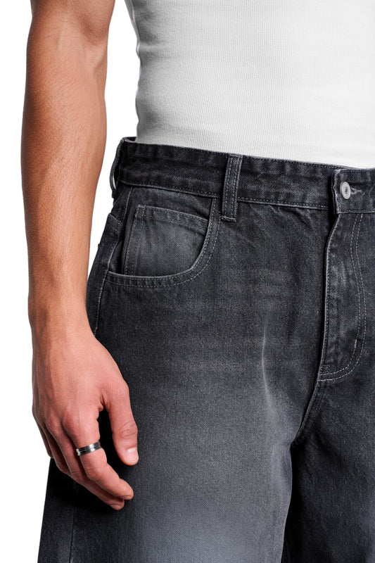 Nahaufnahme der Void Denim Pants mit lässigem Banana-Fit, markantem Used-Look, asymmetrischer Gesäßtasche und silbernem Ring an der Hand. Perfekt für OLAKALA's entspannten Stil.