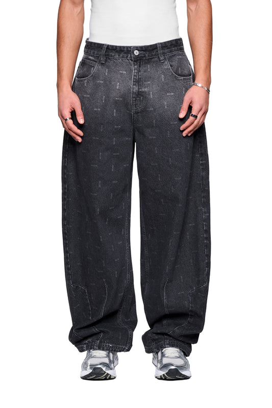 Person trägt Void Denim Pants in Baggy-Banana-Fit mit Used-Optik und subtilen Tonprint, kombiniert mit weißen Sneakers und silbernem Schmuck, vor weißem Hintergrund.