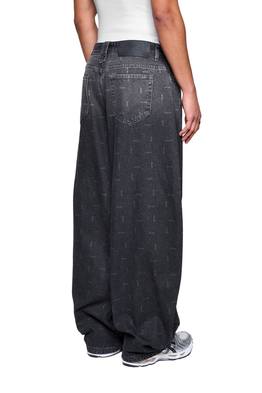 Person trägt Void Denim Pants mit weitem Beinschnitt und Used-Look, kombiniert mit weißem Tanktop und klobigen Sneakers. Klassischer 5-Pocket-Stil mit PU-Patch am Bund.