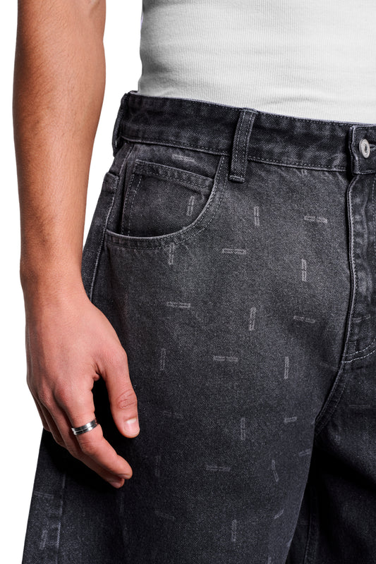 Nahaufnahme der Void Denim Pants mit dezentem Strichmuster, 5-Pocket-Stil, versetzter Seitennaht und asymmetrischer Gesäßtasche. Silverner Ring am Finger.