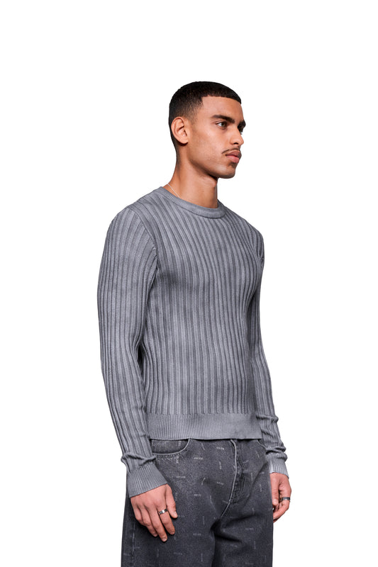 Mann trägt Void Knit Longsleeve mit strukturiertem Finish, kombiniert mit dunklen Jeans und Silberkette. Perfekt als zentrales Outfit-Element oder Layering-Piece.