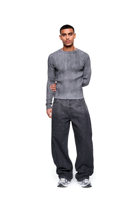 A young man wears the Void Knit long-sleeve shirt with straight sleeves and a crew neck, paired with loose-fitting jeans and chunky sneakers.
