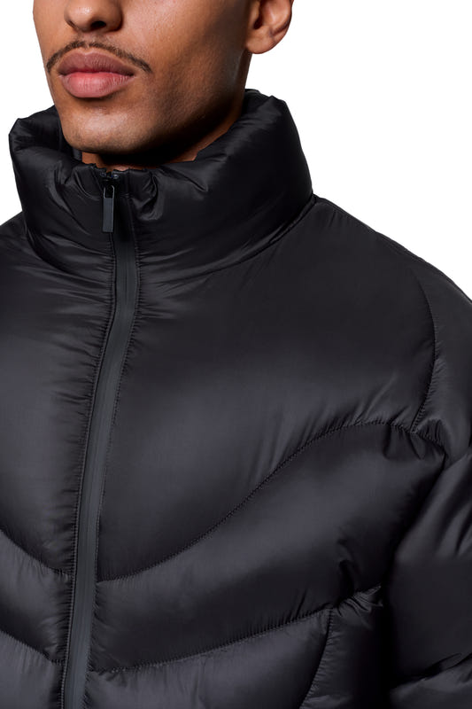 A person is wearing a Void Puffer Jacket with a high stand-up collar and a functional design, including a waterproof front zipper and an adjustable hem, making it ideal for everyday protection and comfort.
