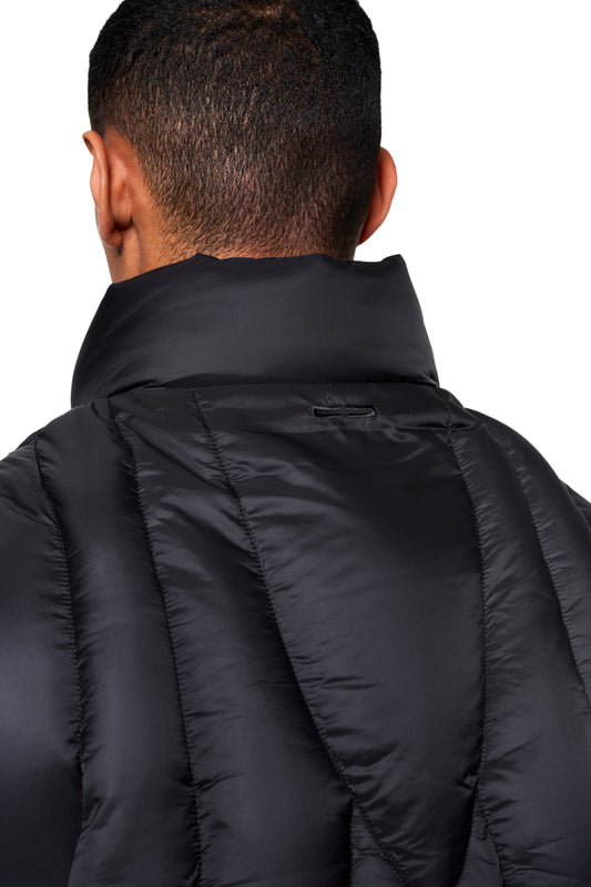 Person von hinten in einer schwarzen, gesteppten Void Puffer Vest mit hochgestelltem Kragen, zeigt sichtbare Nahtlinien der gepolsterten Paneele.