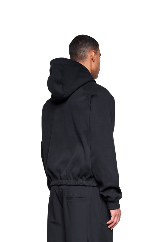 Männliche Rückansicht im Void Rib Hoodie von OLAKALA®, zeigt lässigen, kastigen Schnitt mit markanter Rippstruktur und Raglanärmeln.