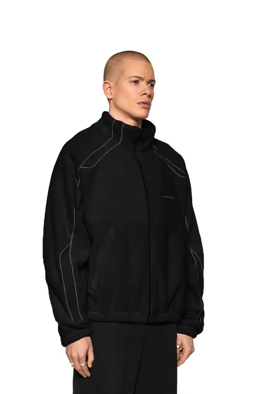 Mann in schwarzer Reflective Fleece Jacket mit OLA KALA Stickerei, reflektierende Nähte, elastische Bündchen, oversized Unisex-Passform, Fokus auf Details am Oberkörper.