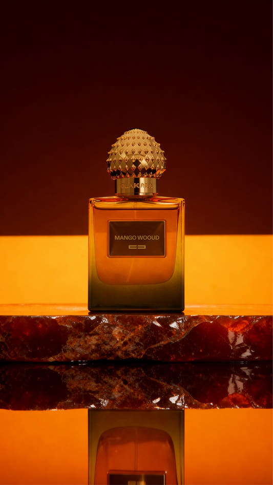 Parfümflakon Mango Wood – amberfarbene Glasflasche mit diamantförmigem Deckel, auf goldbraunem Marmorboden mit Spiegeluntergrund.