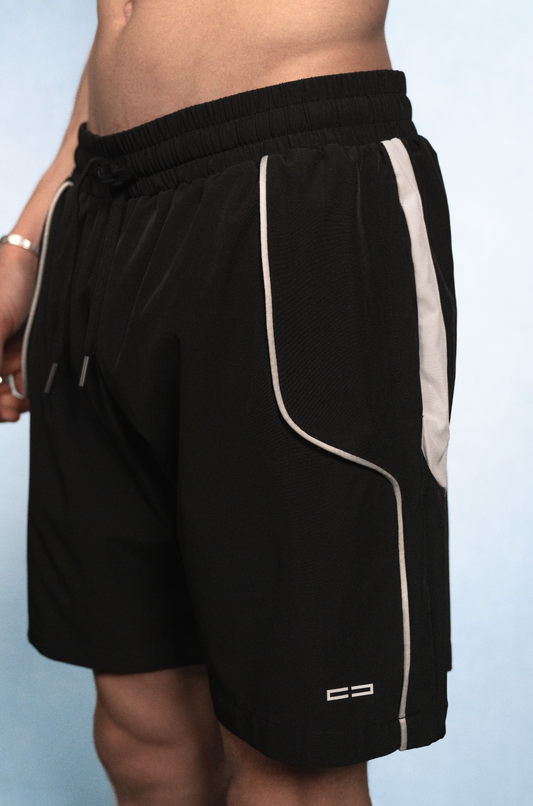 Schwarze Sportshorts mit weißer Kontrastpaspel entlang der Seitentasche/Seitennaht, elastischem Bund mit Kordel und Logo am Bein.