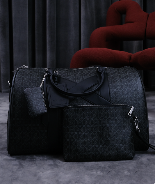 Schwarzes Taschen-Set mit geometrischem Muster: große Reisetasche, passende Umhängetasche, kleines Etui und Clutch; silberne Reißverschlüsse, dunkler Hintergrund.