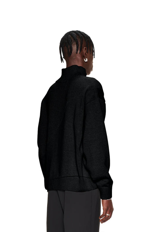 Person trägt CC Knit Halfzip Black, einen Strickpullover mit verschiedenen Mustern und überschnittenen Schultern. Oversized Passform, unisex Design, präsentiert im OLAKALA Online-Shop.