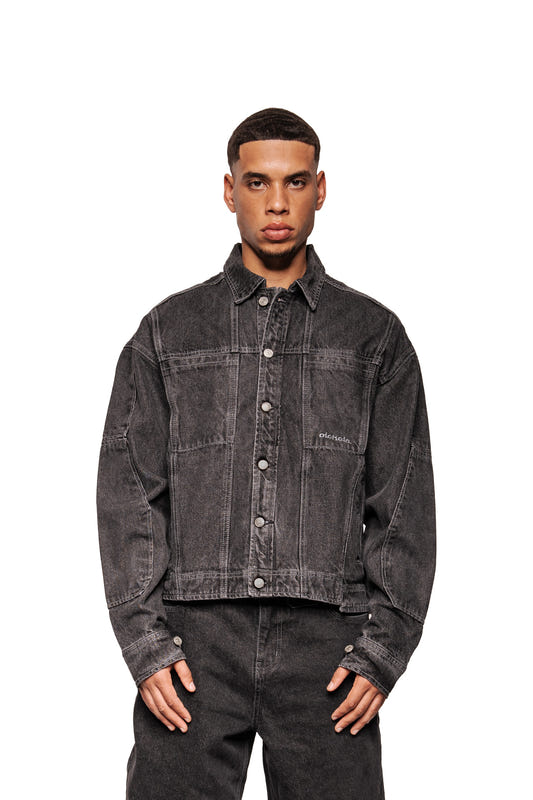 Model wears CC Black Denim Jacket with buttons, breast pockets, embroidered OLAKALA logo, oversized cut and adjustable waistband. Combine with matching denim pants.