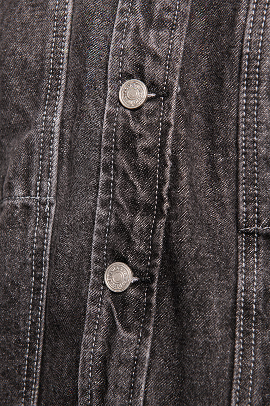 Close-up of the CC Black Denim Jacket with diagonal twill weave, visible dividing seams and two metal buttons on the front placket, characteristic of OLAKALA's oversized unisex design.