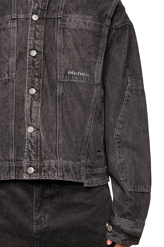 Person trägt CC Black Denim Jacket mit Metallschnappverschlüssen, gesticktem OLAKALA-Logo auf der Brust, und Eingrifftaschen. Oversized, unisex Design.