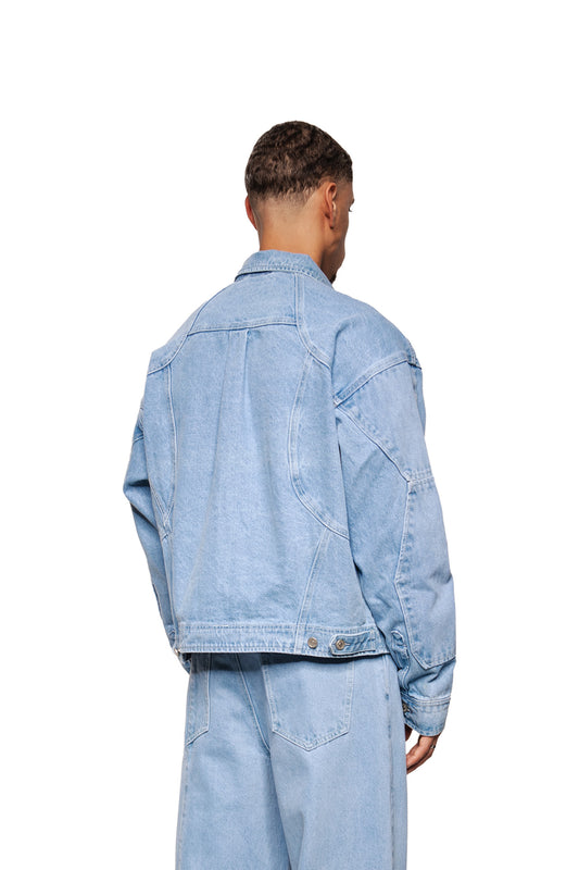 Person from behind in a CC Blue Denim Jacket with dividing seams and adjustable waistband, combined with casual jeans, taken in the studio.