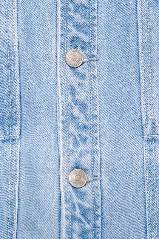 Close-up of the CC Blue Denim Jacket with two metal buttons and distinctive stitching, oversized cut, embroidered OLAKALA logo on the left breast pocket.