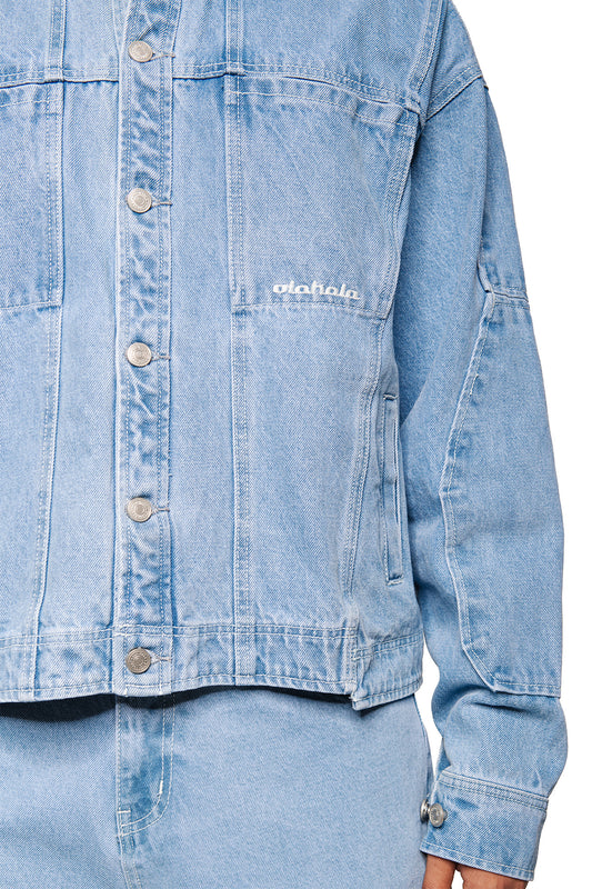 Person wears CC Blue Denim Jacket with metal buttons, embroidered OLAKALA logo on chest, two breast pockets and adjustable waistband, matching light blue jeans.