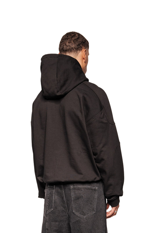 One person wears the Discreet Mask Hoodie Black with oversize cut, ribbed cuffs and embroidered OLAKALA icon, combined with dark jeans, back view.