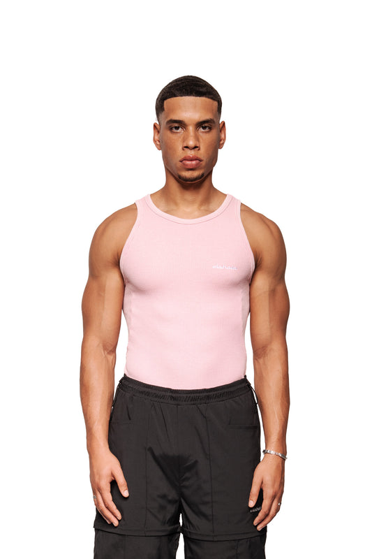 Junger Mann in einem E.O.I Tanktop Cotton Candy mit gesticktem OLAKALA Logo, trägt schwarze Cargo-Shorts, steht frontal vor weißem Hintergrund.