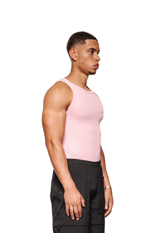 Junger Mann im Profil trägt das E.O.I Tanktop Cotton Candy mit gesticktem OLAKALA Logo und Teilungsnähten, kombiniert mit locker sitzender schwarzer Hose.