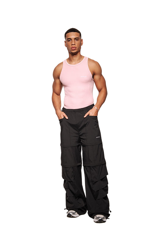 Male model wearing the E.O.I Cotton Candy tank top with ribbed design and embroidered OLAKALA logo, combined with oversized cargo trousers and chunky sneakers.