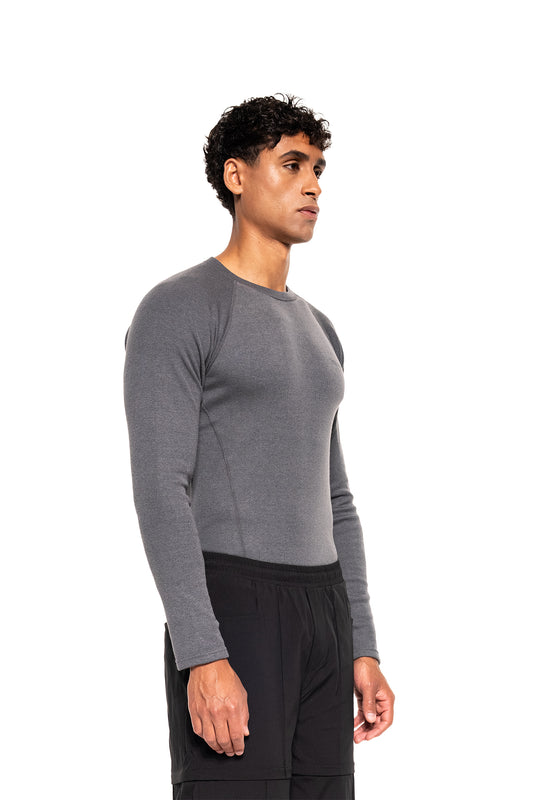 Ein schlanker Mann trägt das Terra Base Layer Longsleeve Gray, präsentiert in Seitenansicht. Ideal als leichte, atmungsaktive Basisschicht für kalte Tage.