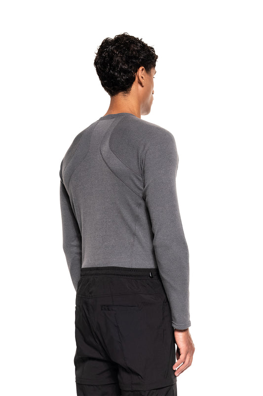 Mann mit Rückenansicht trägt das Terra Base Layer Longsleeve Grau von OLAKALA, kombiniert mit schwarzen Hosen, ideal als vielseitige, atmungsaktive Schicht im Winter.