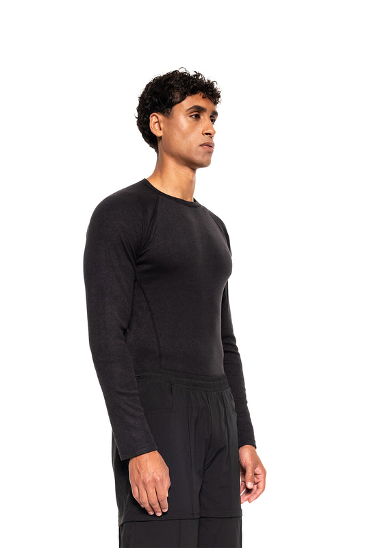 Männliches Modell in Profilansicht trägt das Terra Base Layer Longsleeve Black, ein figurbetontes, atmungsaktives Oberteil mit sportlichem Schnitt und flachen Nähten.