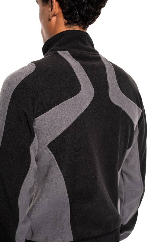 Person wears the Light Fleece Jacket Black & Gray, a lightweight, breathable mid-layer jacket with ergonomic seams and practical zip pockets, ideal for cooler temperatures.