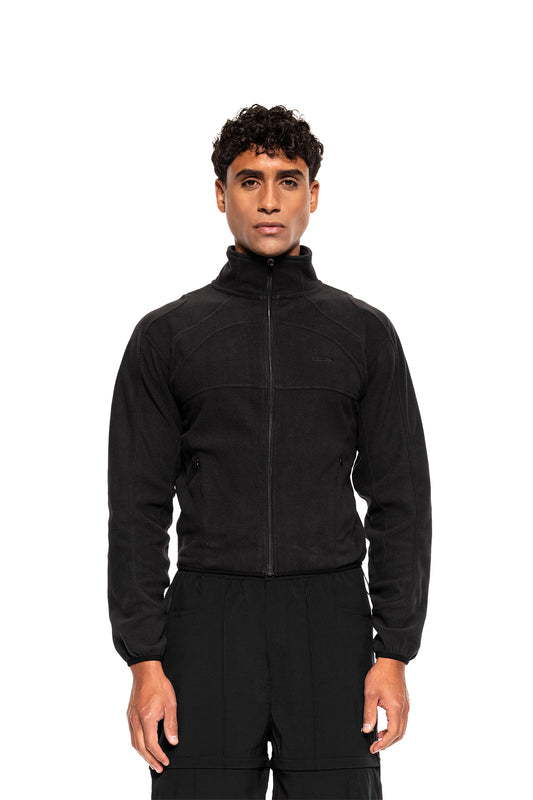 Model trägt Light Fleece Jacket Black mit hohem Kragen und langen Ärmeln, ideal für kalte Tage. Ergonomische Nähte und seitliche Zip-Taschen sichtbar.