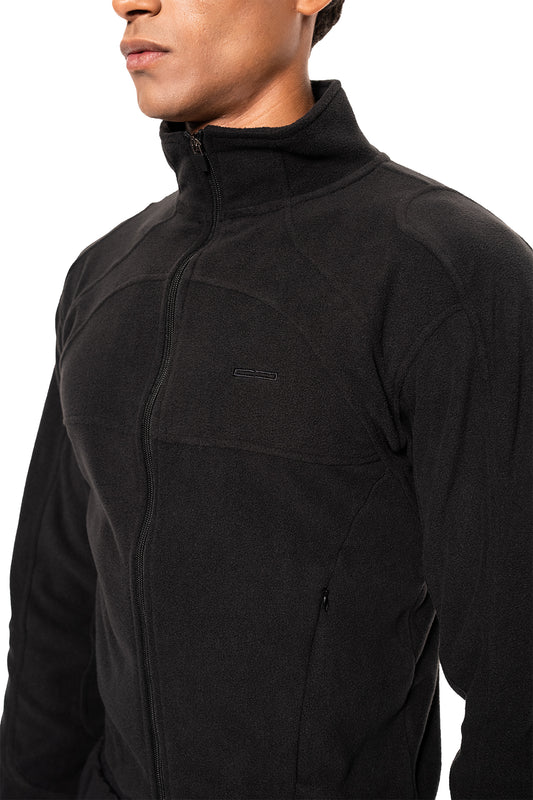 Person trägt die Light Fleece Jacket Black mit hohem Kragen, minimalistischer Design, Brusttasche und seitlichen Reißverschlusstaschen, ideal als Midlayer für kalte Tage.