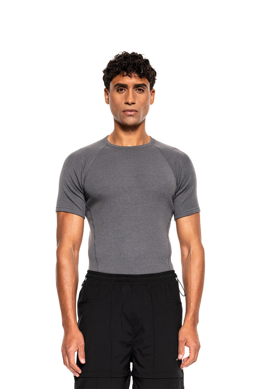 Mann trägt Terra Base Layer T-Shirt Gray, eng anliegend, atmungsaktiv, kombiniert mit lockerer Hose. Perfekt als vielseitige Schicht für kältere Tage.