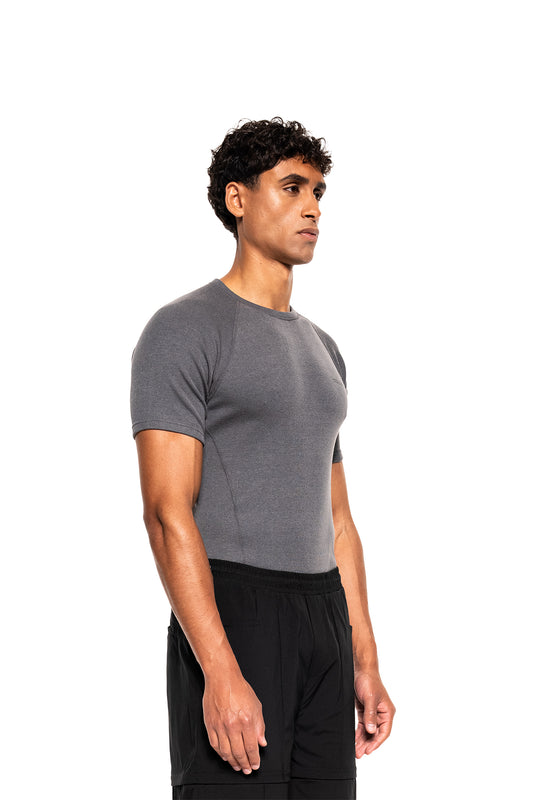 Junger Mann im Profil trägt das Terra Base Layer T-Shirt Gray, kombiniert mit schwarzen Shorts, ideal für sportliche Aktivitäten dank atmungsaktivem, leichtem Material.