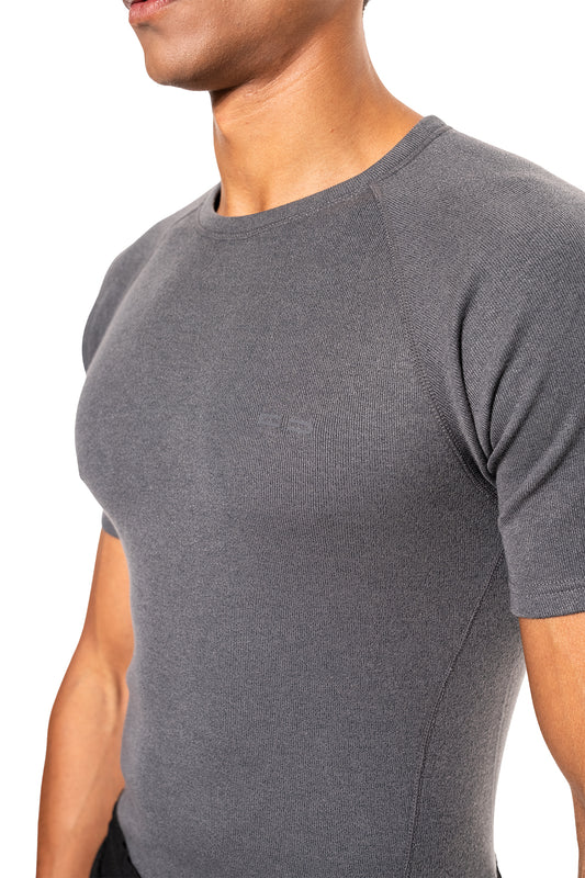 Person trägt ein Terra Base Layer T-Shirt Gray mit kleinem Logo links auf der Brust; zeigt Textur und Passform an Schultern und Brust.