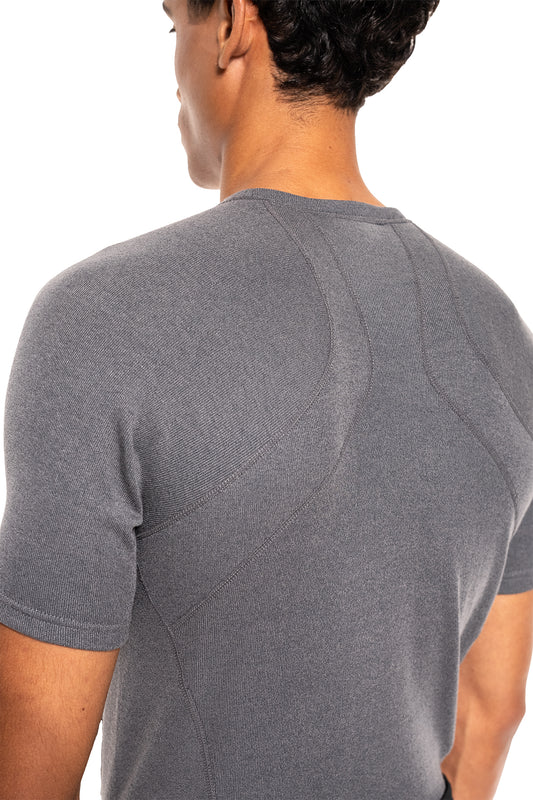 Person in anliegendem, heather-grauem Terra Base Layer T-Shirt, zeigt texturiertes Strickmuster und gebogene Nähte, betont sportlichen und funktionalen Schnitt für vielseitigen Einsatz.