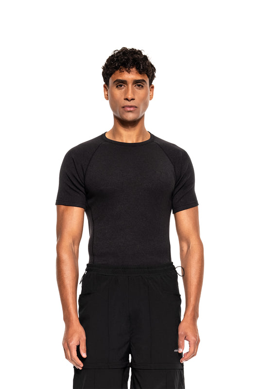 Model trägt das Terra Base Layer T-Shirt Black, ein figurbetontes, atmungsaktives Shirt, ideal für vielseitige Schichtung und sportliche Aktivitäten im offiziellen OLAKALA® Onlineshop.
