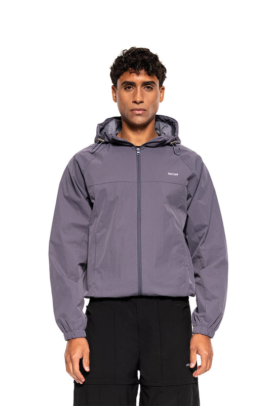 Männliches Model trägt den Windbreaker Icon Gray mit Kapuze und elastischen Bündchen, ideal für Sport und Alltag.