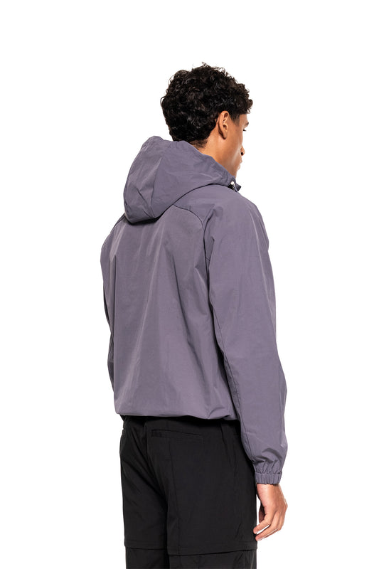 Young man wears Windbreaker Icon Gray with hood and elastic cuffs, ideal for sports and everyday wear.