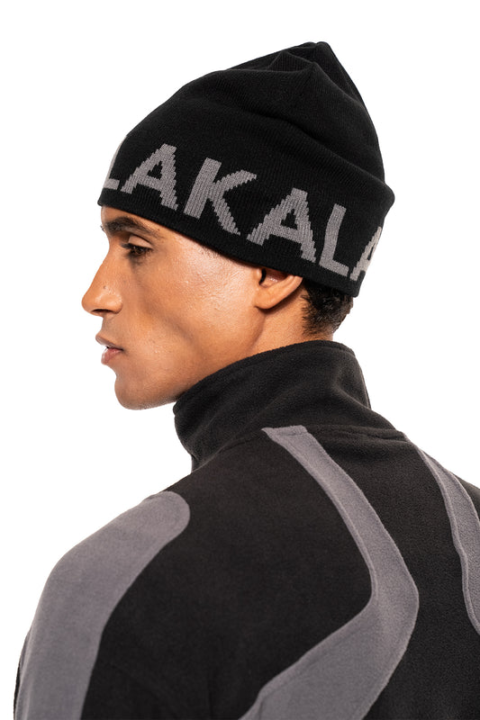Junger Mann trägt die Light Logo Beanie Black, ein leichtes, formbeständiges Accessoire mit eingestricktem Logo, passend zum OLAKALA® Fleece-Oberteil.