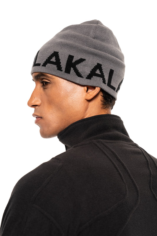 Mann trägt Light Logo Beanie Grau mit schwarzem Schriftzug an der Krempe und schwarzer Fleecejacke, ideal für kalte Tage, von OLAKALA.