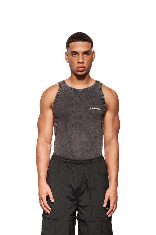 Junger Mann trägt das Echoes Tanktop mit OLAKALA-Logo auf der Brust, taillierter Schnitt, in Washed-Optik, kombiniert mit lockeren Cargo-Hosen.