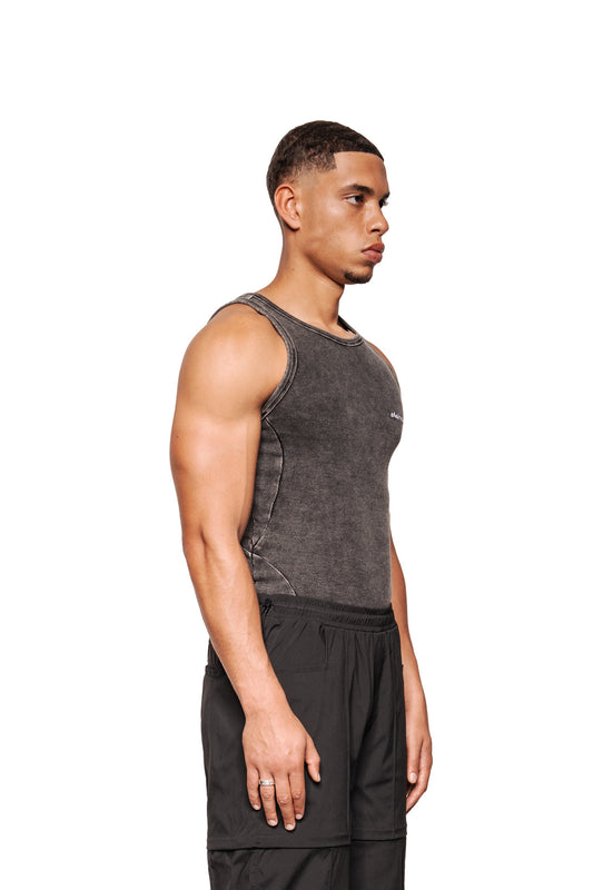 Junger Mann im Profil trägt das Echoes Tanktop mit Seitennähten und gesticktem OLAKALA-Logo auf der Brust, präsentiert in enger Passform.