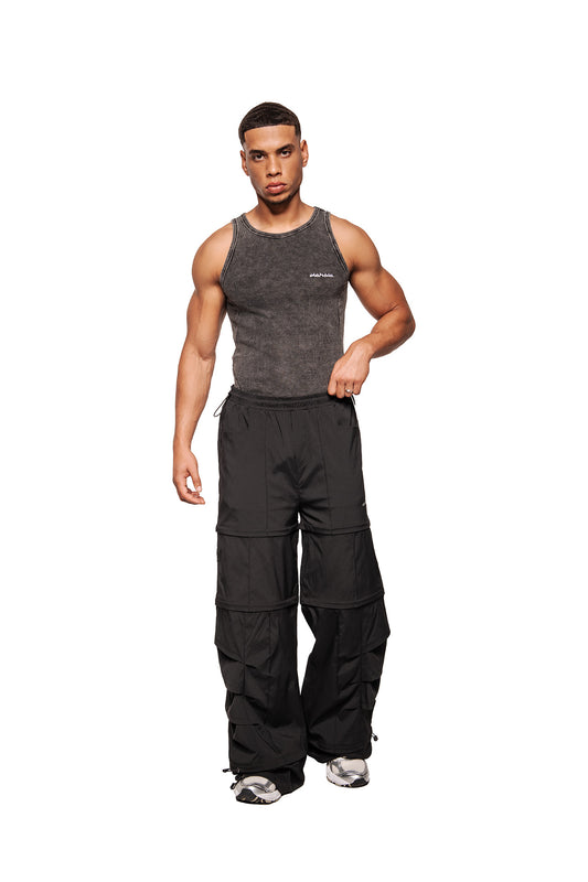 Male model in Echoes tank top with ribbed design, high round neck and embroidered OLAKALA logo, combined with wide black cargo pants.